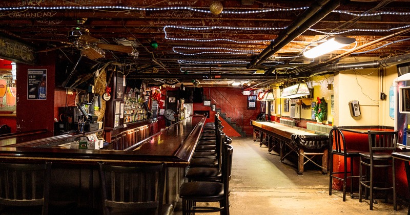 Interior, downstairs area, bar with bar stools on the left, shuffle board table on the right