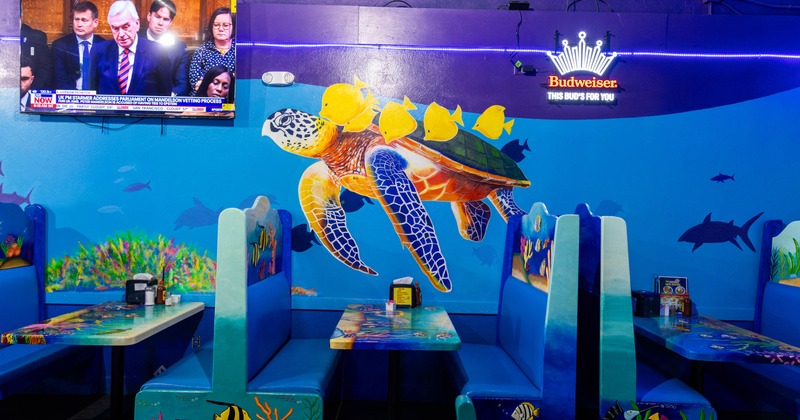 An indoor restaurant mural featuring a sea turtle with yellow fish on its back