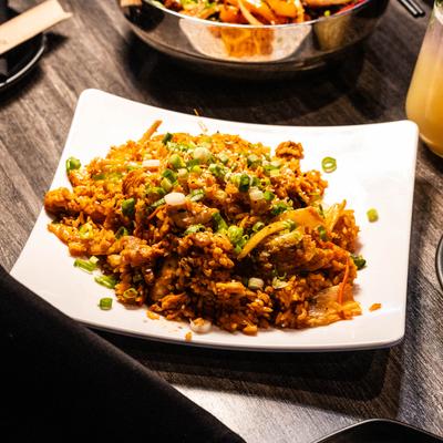 Spicy kimchi fried rice on a white plate, topped with green onions.