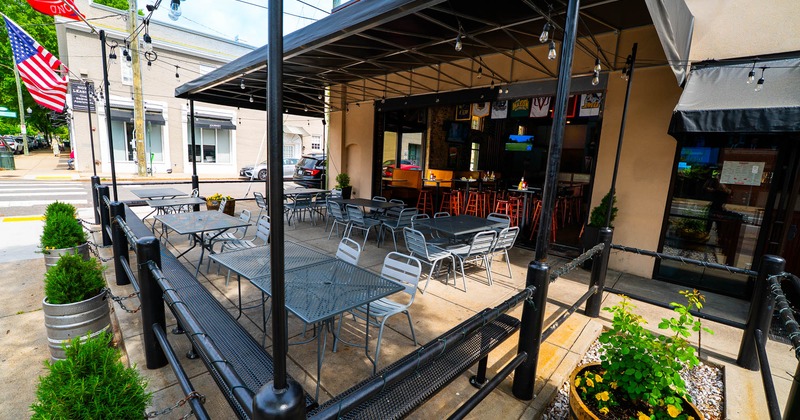 Exterior, patio, partially covered seating area, tables with chairs, long metal bench with tables