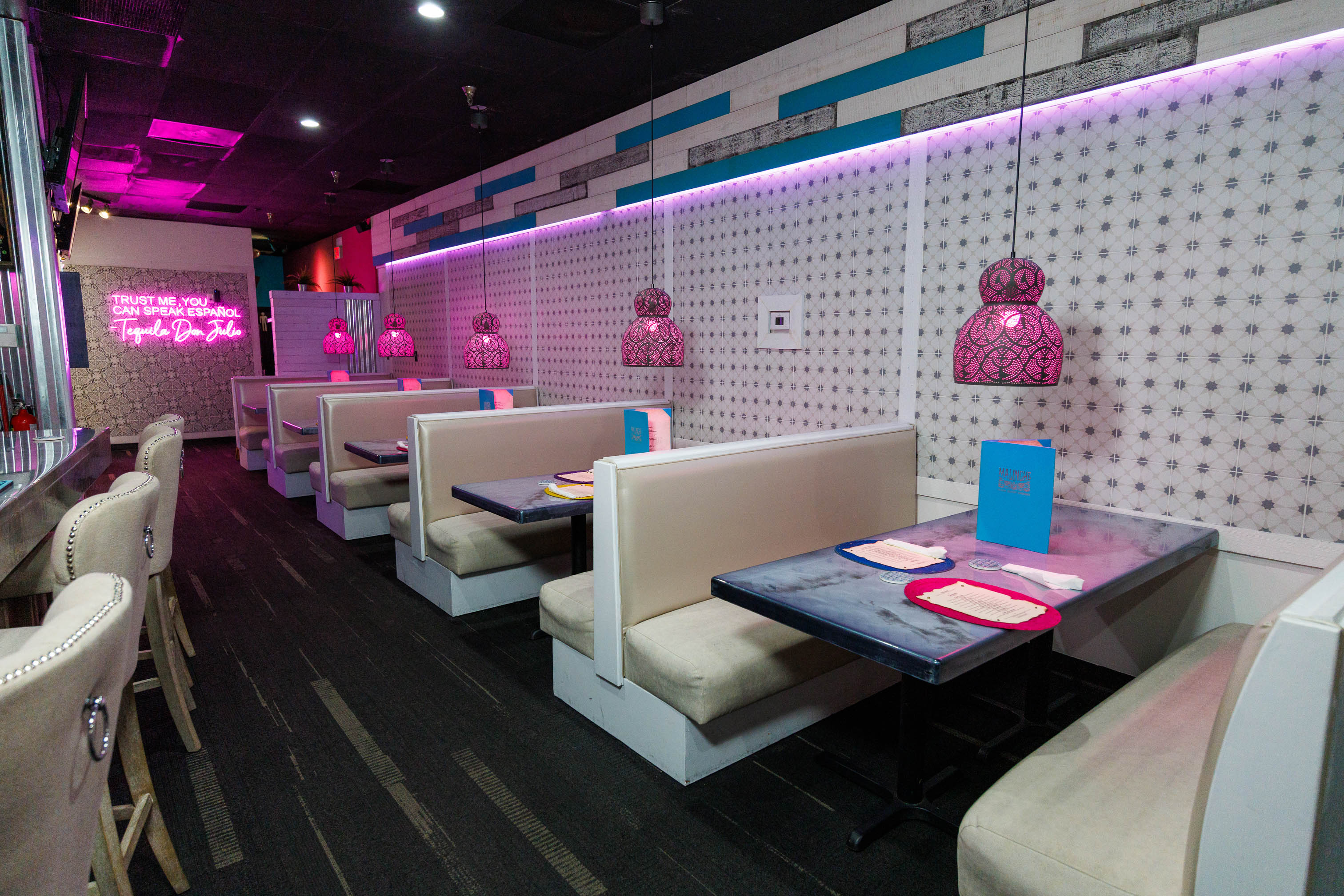 Restaurant interior with booths, set tables, wall paneling and hanging lights