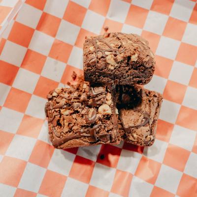Chocolate brownies on a red and white checkered paper.