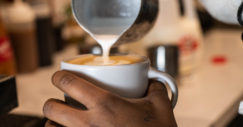 hands pouring a latte