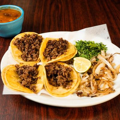 Taquitos Mexicanos served with grilled onion, cilantro, lime wedges and consomme.