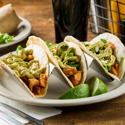 Three chicken tacos served with lime wedges