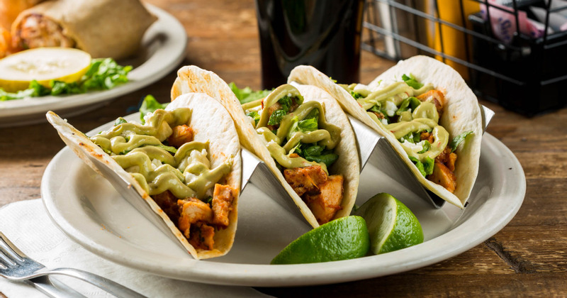Three chicken tacos served with lime wedges