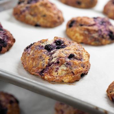 Freshly baked blueberry drop scones on a baking tray lined with parchment paper.