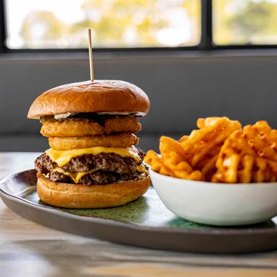 Double cheeseburger with onion rings and waffle fries.