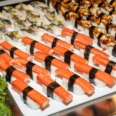 Rows of crab stick nigiri served alongside various sushi rolls.