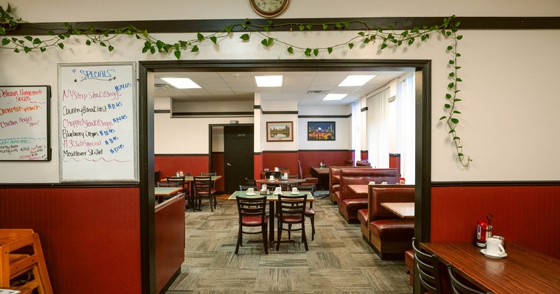 Interior with red booths, wooden tables, and a whiteboard listing daily specials