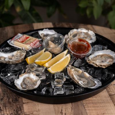 Fresh raw oysters served on ice with sauces, lemon wedges and crackers.