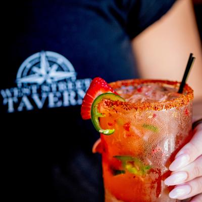 A person holds a spicy strawberry margarita with a chili-salted rim.