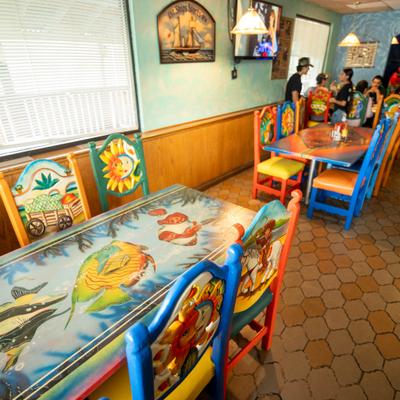 Interior featuring hand-painted wooden tables and bright blue, yellow, and red chairs.
