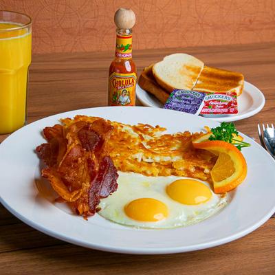 Two sunny side up eggs, bacon, hash browns, toast, jam, hot sauce, and orange juice.
