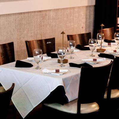 Table seting featuring a white table cloth, side plates, napkins, glasses and table lamps.