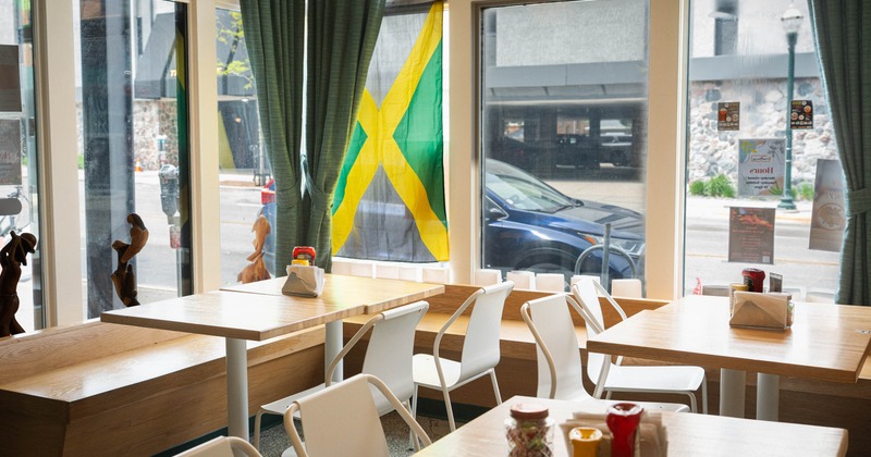 Interior of a cafe with tables, chairs, condiments, and a Jamaican flag