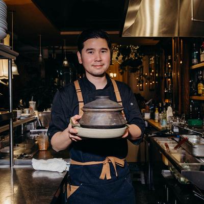 Chef holding a clay pot.