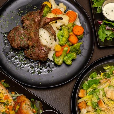 Lamb chops with sides served alongside other dishes.