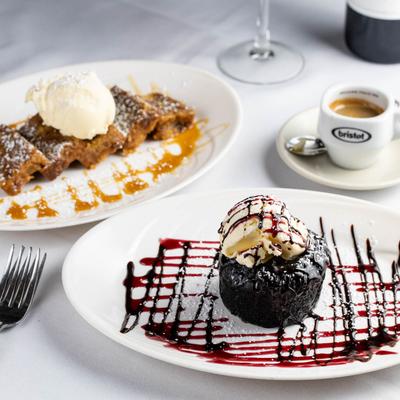 Bread pudding, chocolate lava cake, and a cup of espresso on a table.
