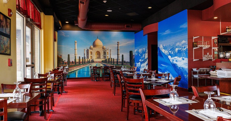 Interior, wide shot of the dining room, tables and chairs, over the wall mural of Taj Mahal