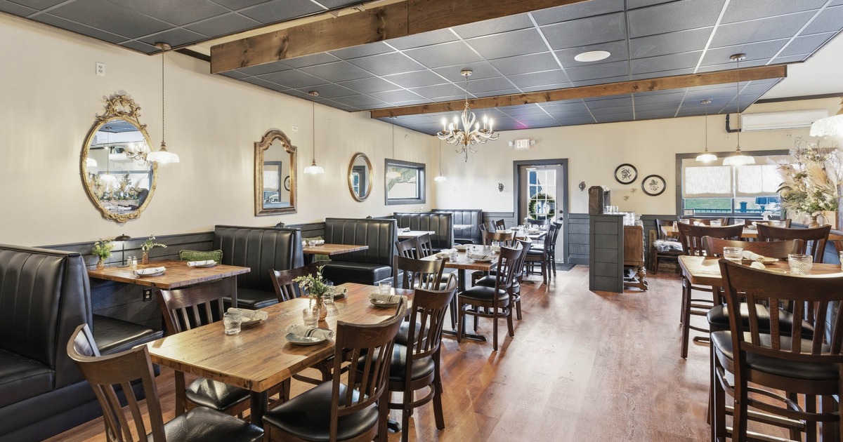 Restaurant interior with wooden tables, cushioned chairs, and decorative mirrors