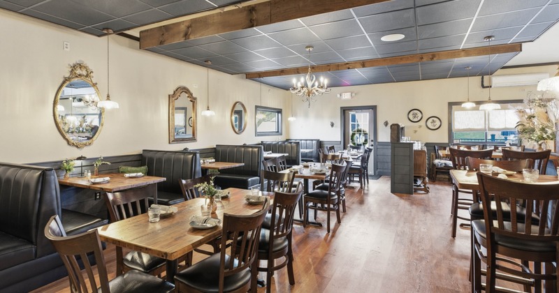 Restaurant interior with wooden tables, cushioned chairs, and decorative mirrors