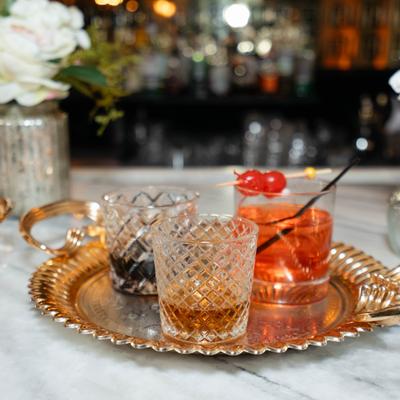 Two glasses with spirits and a cocktail served on a golden tray.