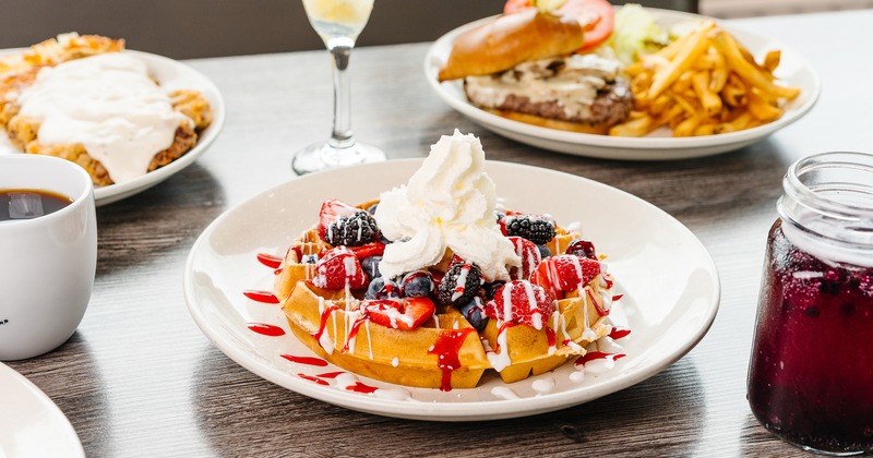 Very Berry Waffle served on the table alongside other dishes and a cocktail