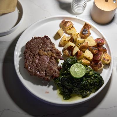 A meal consisting of steak, roasted potatoes, and sauteed kale.