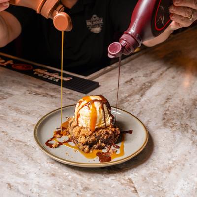 Sea Salt Caramel Brownie being drizzled with chocolate and caramel sauces.