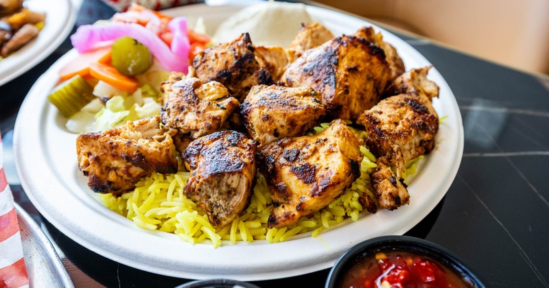 Chicken kebab with yellow rice, vegetables, and garlic sauce