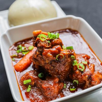 Bowl of oxtail stew served with fufu dough ball.