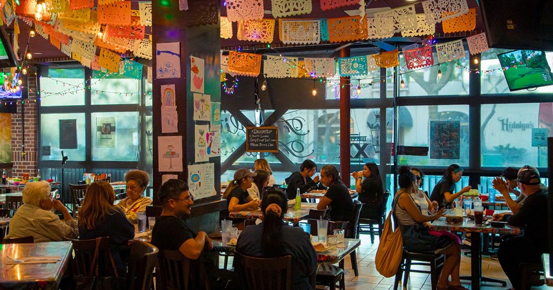 Interior, dining area full of guests chatting and enjoying their food and drinks