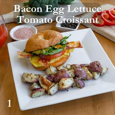Bacon Egg Lettuce Tomato Croissant sandwich with a side of roasted potatoes
