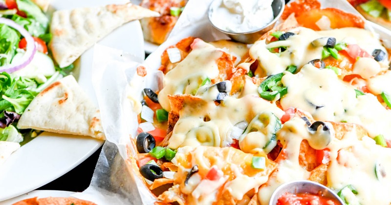 Loaded nachos with tomatoes, peppers, onions, olives, and cheddar cheese