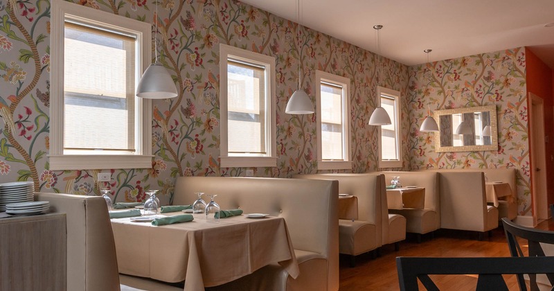 Set dining booths by windows with floral wallpaper