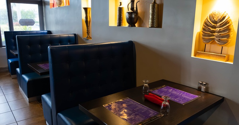 Interior view of a restaurant with blue booths, dark wooden tables, and decorative wall