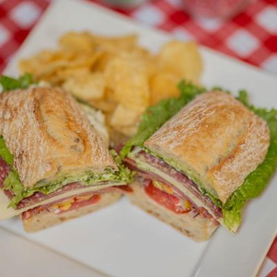 The Italian Club sandwich sliced in half and served with a side of chips.