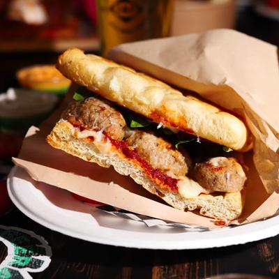 Meatball sandwich with red sauce, cheese, and basil.