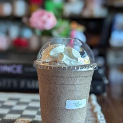 Drink topped with whipped cream, served in plastic, take-away cup.