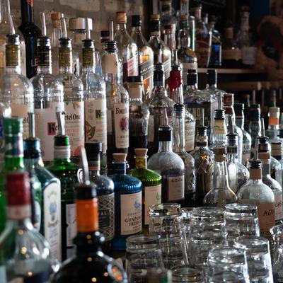 Lined up bottles of liquor behind the bar, side view.