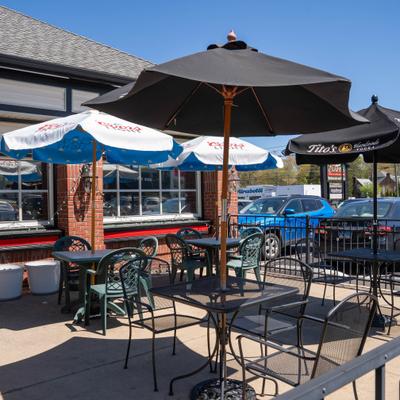 Fenced patio area with tables, chairs and branded umbrellas.