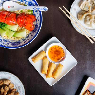 Assorted Asian dishes including lobster noodle soup, dumplings, and spring rolls.