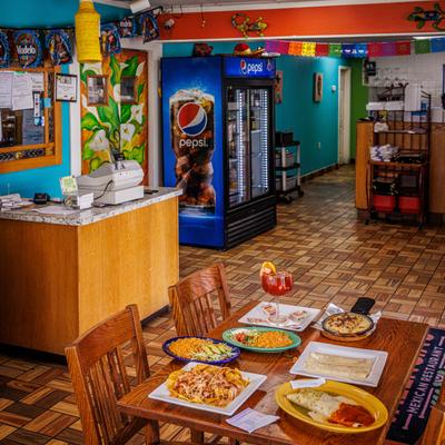 Interior featuring a table set with multiple plates of food, a counter area and a refrigerator unit.