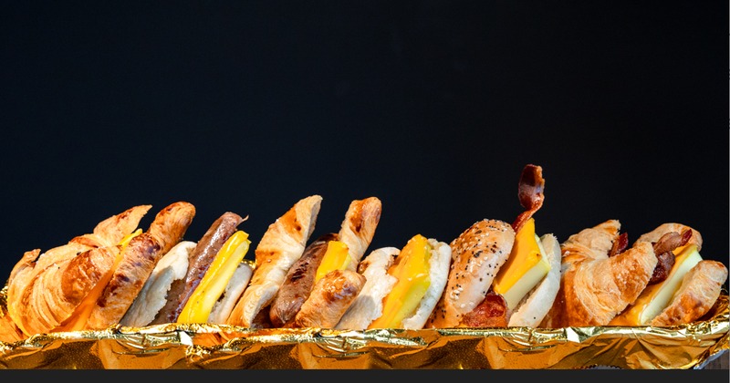 Multiple breakfast sandwiches lined up in a row