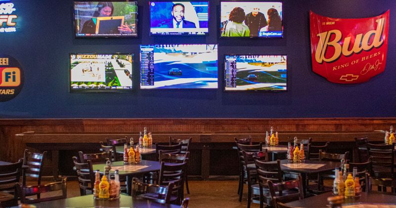 Several TVs mounted on wall in dining area