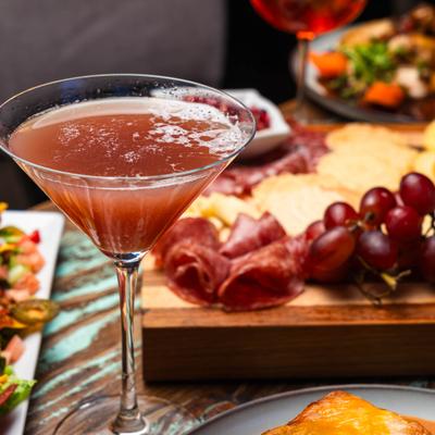 Cocktail in martini glass served on the table with food.