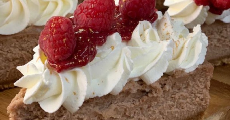 Cheesecake topped with  whipped cream and raspberries