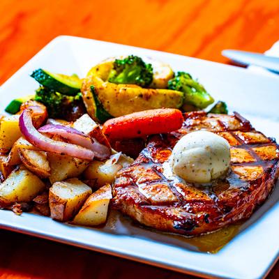 Grilled rib eye steak with grilled potatoes and onions, and sauteed vegetables.