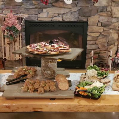 A cozy holiday spread of assorted appetizers in front of a stone fireplace.
